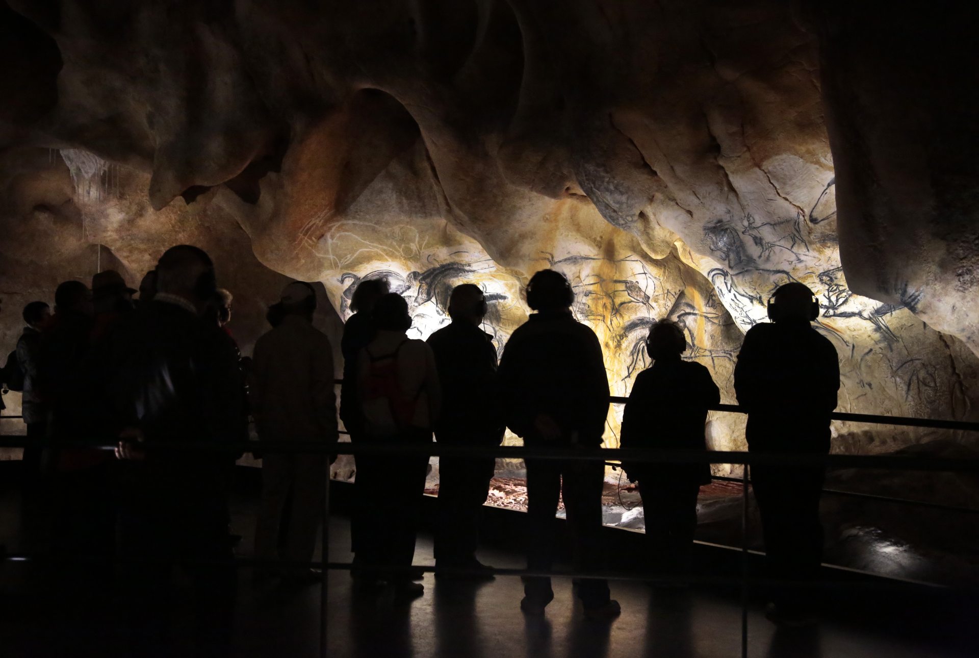 Emerveillement des visiteurs devant le panneau des chevaux dans la restitution de la grotte.